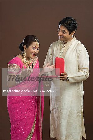 Man giving a jewelry box to his wife in present