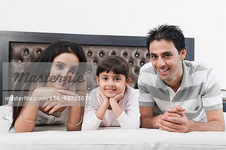 Portrait of a couple lying on the bed with their daughter