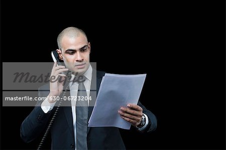 Businessman talking on the telephone and looking at a document