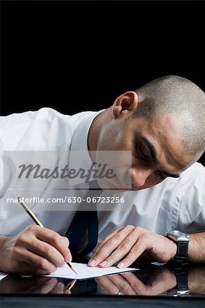 Businessman sitting at a table and writing on a sheet of paper