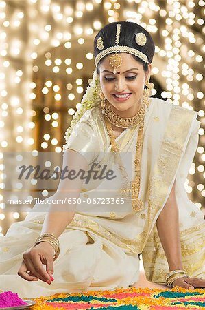 Indian woman in traditional clothing making rangoli at Durga festival