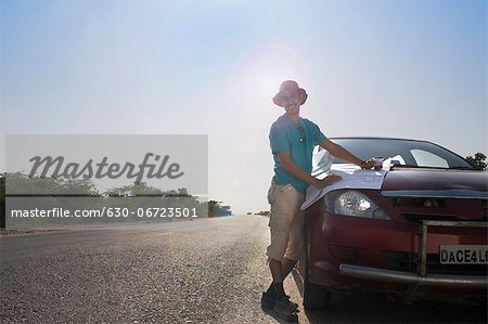 Man holding a map on a car hood