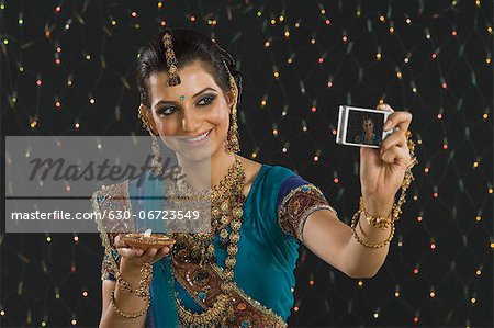 Woman holding an oil lamp and taking a picture of herself with a digital camera