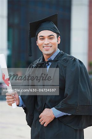 Male graduate student holding a diploma and smiling in university campus
