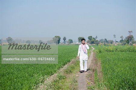 Farmer talking on a mobile phone in the field, Sonipat, Haryana, India