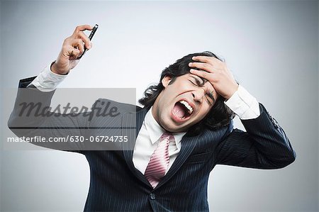 Frustrated businessman holding a mobile phone and shouting