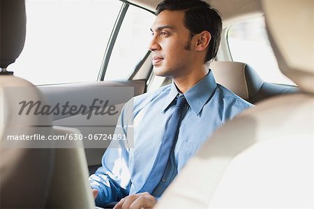 Bengali businessman using a laptop in a car