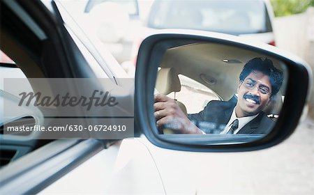 Reflection of a South Indian businessman in the side view mirror of a car