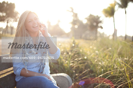 Young Woman Sitting on Bench at Beach using Cell Phone, Jupiter, Palm Beach County, Florida, USA