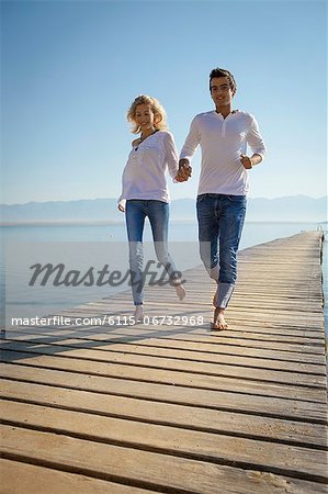 Croatia, Young couple runs across boardwalk, by the sea