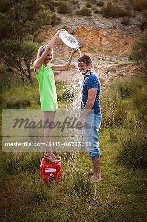 Croatia, Dalmatia, Young woman pouring water on man, side view