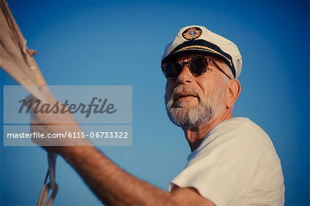 Croatia, Senior man with captain's hat steering sailboat