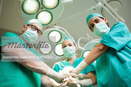 Surgical team joining hands in a surgical room