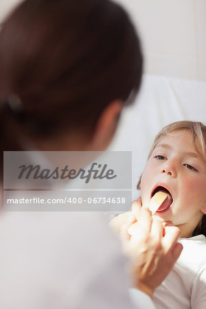 Doctor examining the mouth of a child in hospital ward