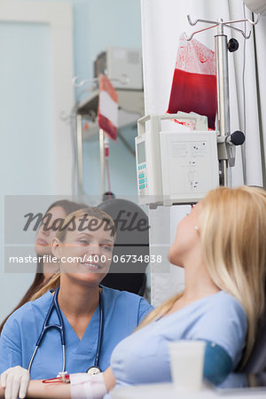Smiling nurse looking at a female patient in hospital ward