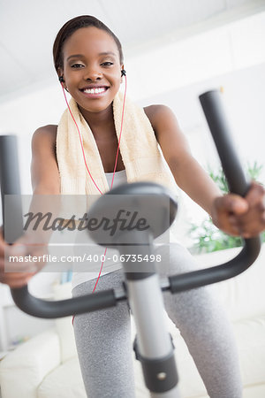 Front view of a black woman doing exercise bike in a living room