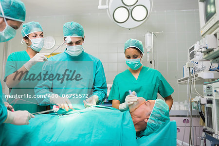 Nurse drying forehead of a concentrated surgeon in an operating theatre