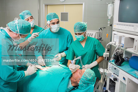 Nurse drying forehead of a surgeon next to a patient in an operating theatre