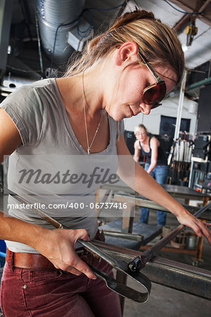 Pretty glass sculptor shaping tiny object on workbench