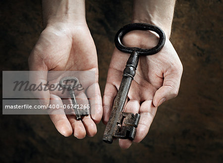 Man holding a big and a small key in his hands.