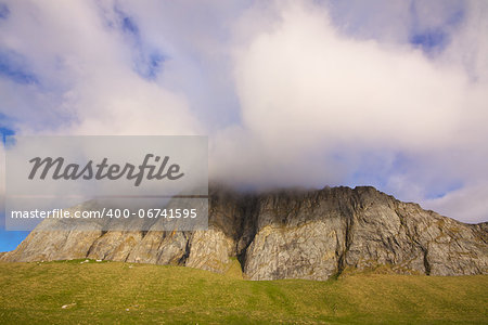 Picturesque cliff with clouds forming on the top, island of Vaeroy, Lofoten, Norway