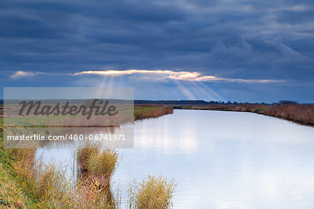 sunbeams through clouded storm sky over river