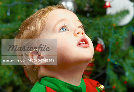 Cute 1 year old baby boy at the Chriistmas tree.