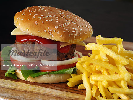 Photo of a hamburger and french fries on a wooden board.
