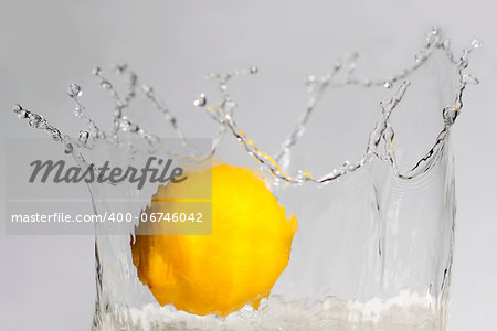 Lemon splashing into clear water on white background.