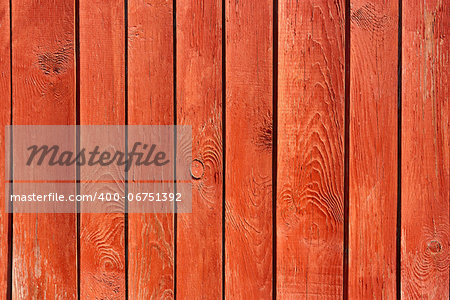 Part of vertical ancient wooden fence painted in red. Fine sunny weather