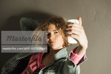 Teenage Girl taking Self Portrait with Camera Phone, Studio Shot