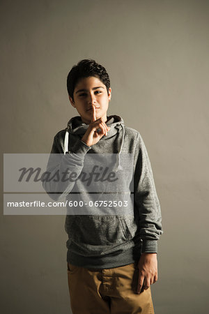 Portrait of Teenage Boy with Finger to Lips, Studio Shot