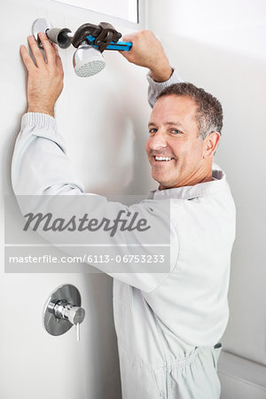 Plumber working on shower head in bathroom