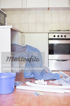 Woman working under kitchen sink