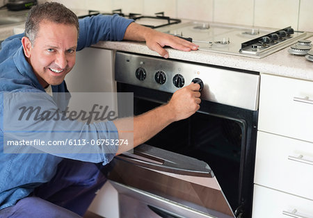 Electrician working on oven in kitchen