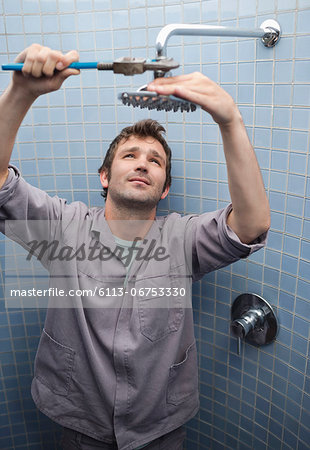 Plumber working on shower head in bathroom