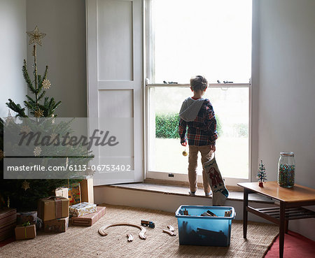 Boy holding Christmas stocking at window