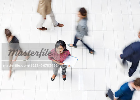 Businesswoman smiling in busy office hallway