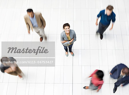 Businesswoman standing in busy office hallway Businesswoman standing in busy office hallway