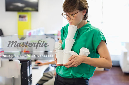 Businesswoman balancing empty coffee cups
