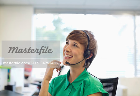 Businesswoman talking on headset at desk