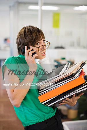 Businesswoman with folders talking on cell phone