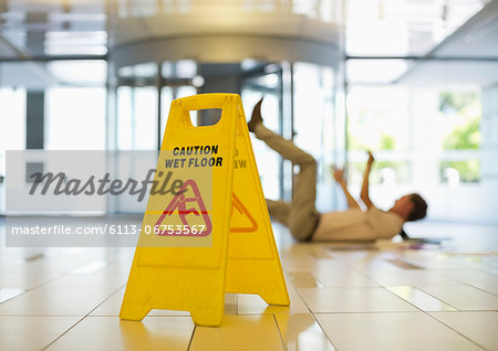 Businessman slipping on wet office floor