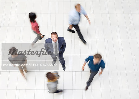 Businessman standing in busy office hallway Businessman standing in busy office hallway
