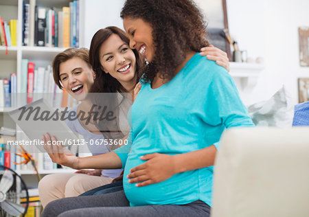 Pregnant woman using tablet computer with friends