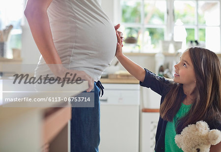 Girl holding pregnant mother's belly