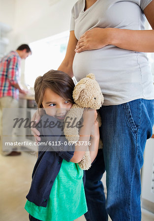 Girl hiding behind pregnant mother