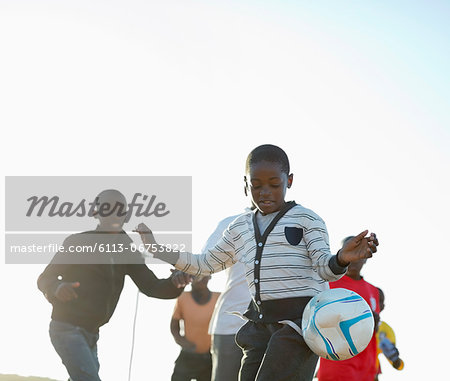 Boys playing soccer together in dirt field