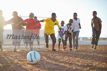 Boys playing soccer together in dirt field