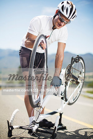 Man adjusting bicycle on rural road